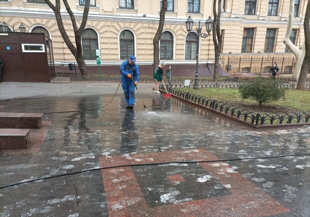 Комунальник відмиває фарбу, яку розлили в Міському саду. 