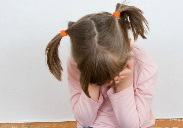 Девочка закрывает лицо руками. 