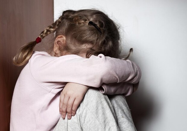 Девочка сидит, спрятав лицо. 