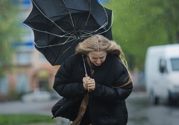 Девушка идет по улице во время сильного ветра. 