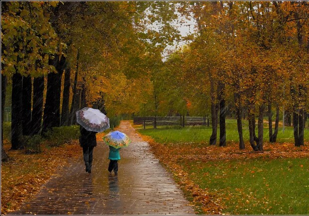 Жінка й дитина йдуть вулицею під час дощу. 