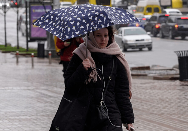 Дівчина йде вулицею під час дощу. 