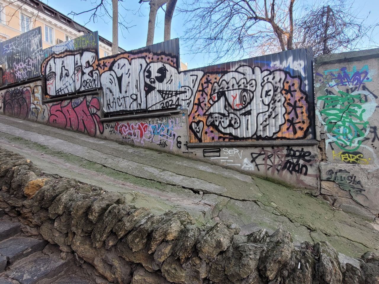 Стены и забор по бокам лестницы щедро расписаны "народным творчеством".