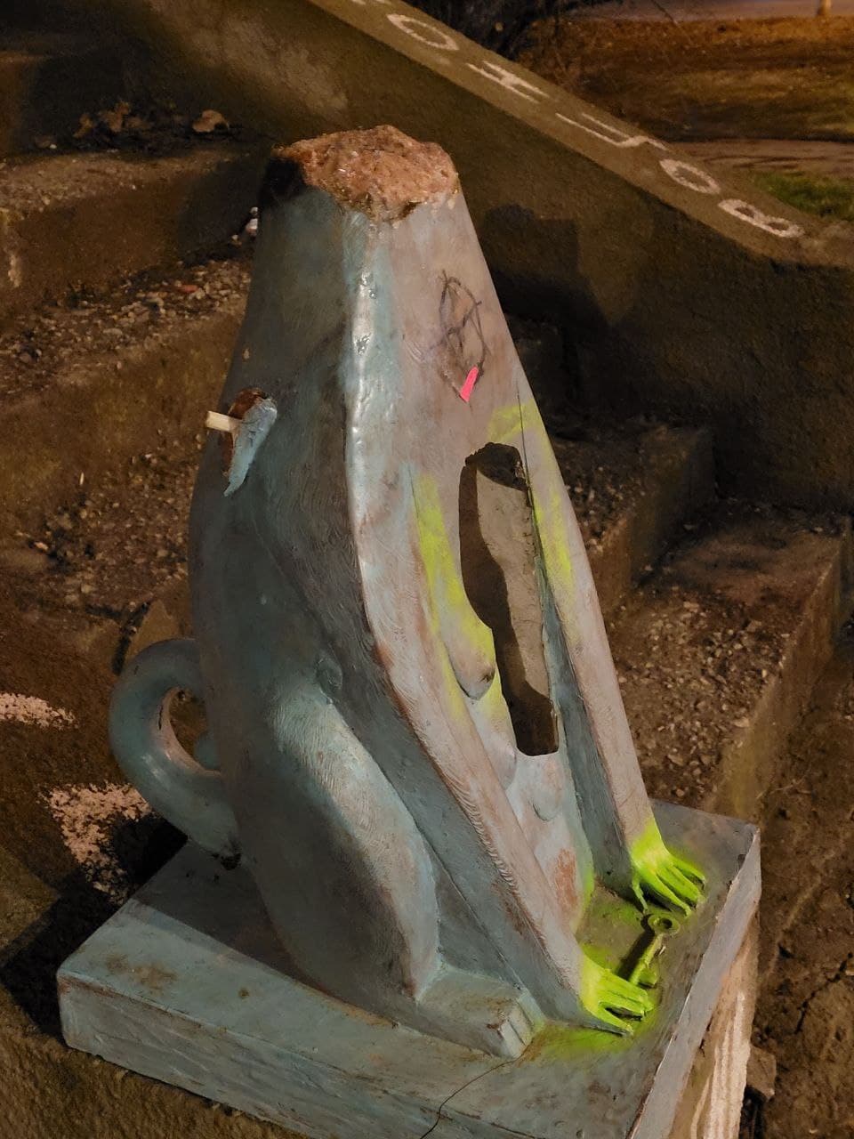 На месте левого крылышка скульптуры виднеется окурок сигареты.